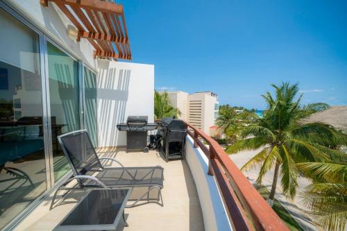 a balcony of a building with chairs and palm trees at Beachfront Penthouse with 3 Bedrooms & Ocean View - Las Nubes in Playa del Carmen