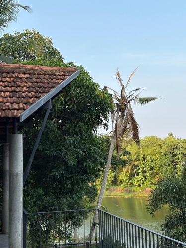 a palm tree leaning over a fence next to a river at Ripples Cove Retreat - Your dream Lakeside getaway in Paravūr