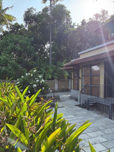 a house with a porch and some plants at Ripples Cove Retreat - Your dream Lakeside getaway in Paravūr