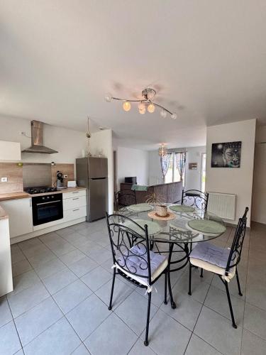 une cuisine et une salle à manger avec une table et des chaises en verre dans l'établissement Namina, à Pleslin-Trigavou