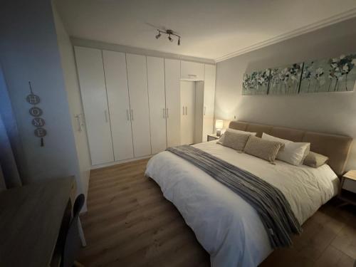 ein Schlafzimmer mit einem großen Bett mit weißen Schränken in der Unterkunft Serene waterfront escape! Luxury, King bed! in Durbanville