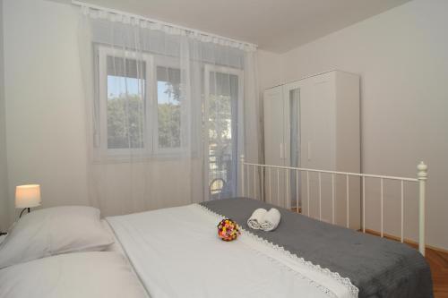a white bedroom with a bed with flowers on it at Apartman Mario in Zadar