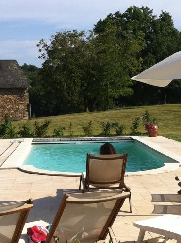 une femme assise sur une chaise à côté d'une piscine dans l'établissement DOMAINE DE LA GANERAIE, exceptional setting, à Saint-Méard