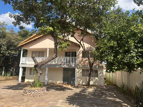 a house with a balcony and a tree at Pousada Rio Cipó in Serra do Cipo