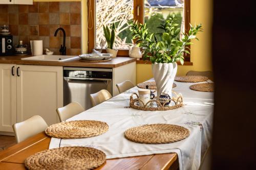 eine Küche mit einem Tisch mit einem weißen Tischtuch und Stühlen in der Unterkunft Domek Stroma 13 in Zakopane