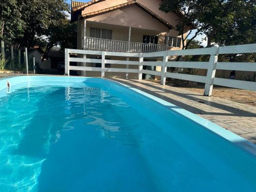 a blue swimming pool next to a white fence at Pousada Rio Cipó in Serra do Cipo