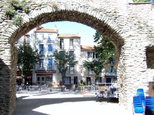an archway in a building with chairs in a courtyard at Poppys in Céret
