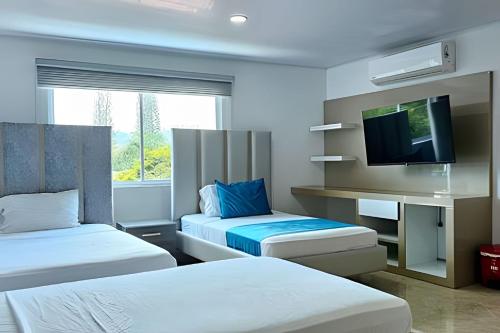 a hotel room with two beds and a flat screen tv at Hotel Lotto Boutique in Cali