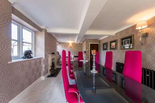 a room with a long table and pink chairs at Hall O'Coole in Nantwich