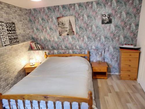 a bedroom with a bed and a wall with wallpaper at Charmante maison à Cérences avec jardin de 55 m² in Cerences