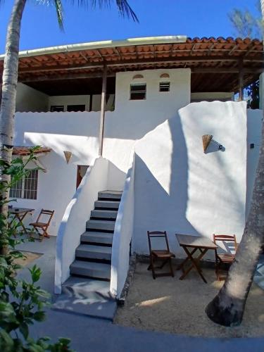 a white building with stairs and chairs and a table at Pousada Unidos in Jijoca de Jericoacoara