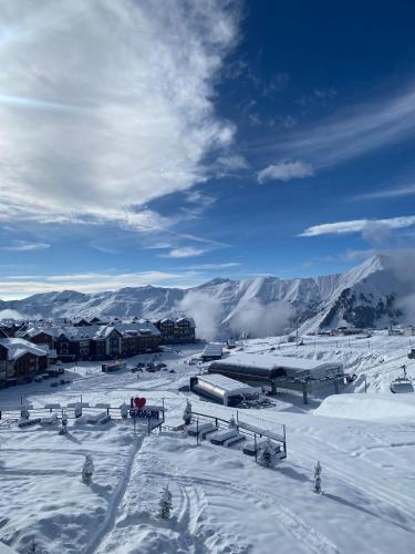 a snow covered town with buildings and a mountain at Go-Gudauri The Atrium Residence in Gudauri