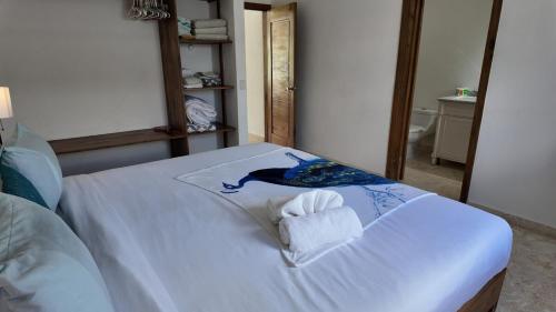 a white bed with a towel and a mirror at La Fenice Beachfront Apartment in Las Terrenas