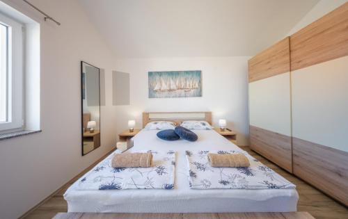 a white bedroom with a large bed with two pillows at Apartmani Lucija in Povljana