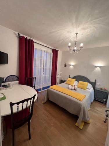 ein Schlafzimmer mit einem Bett mit gelben Kissen und einem Tisch in der Unterkunft Chambres d'hôtes La Rose Des Sables in Les Herbiers
