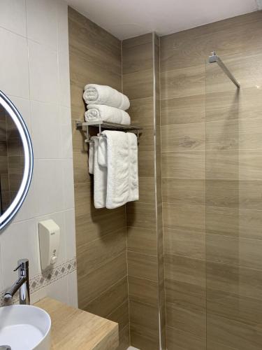 a bathroom with a shower and a sink and towels at Hostal el Rocio in Paracuellos de Jarama