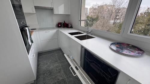 une cuisine blanche avec un évier et une fenêtre dans l'établissement l'emeraude de Nanterre, à Nanterre