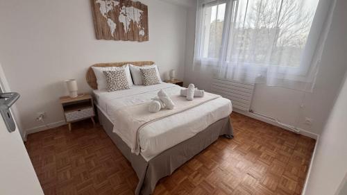 une chambre avec un lit avec des draps blancs et une fenêtre dans l'établissement l'emeraude de Nanterre, à Nanterre
