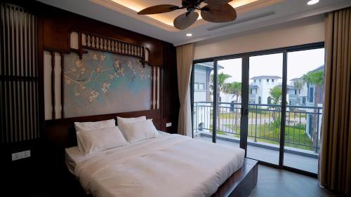 a bedroom with a large bed and a large window at Annam Villa Sonasea Vân Đồn in Thâm Câu