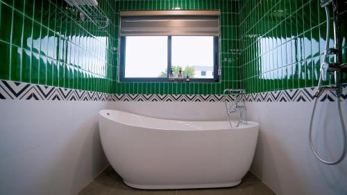 a green tiled bathroom with a tub and a window at Annam Villa Sonasea Vân Đồn in Thâm Câu