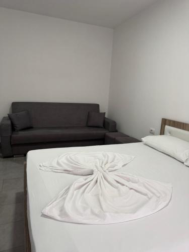 a white bed in a room with a couch at Studio holidays in Shëngjin