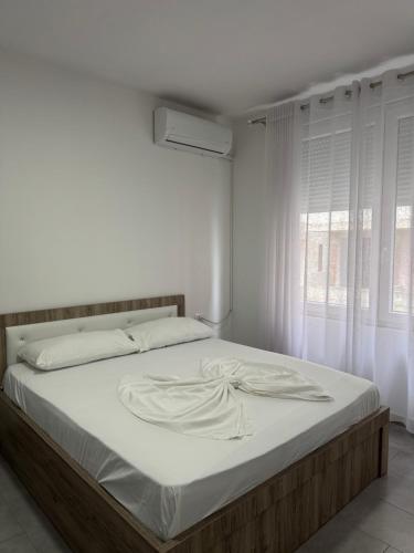 a bedroom with a bed with white sheets and a window at Studio holidays in Shëngjin