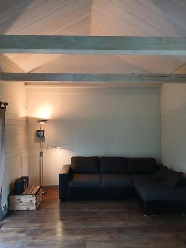 a living room with a black couch in a room at Arakaoja saunamaja in Nepste