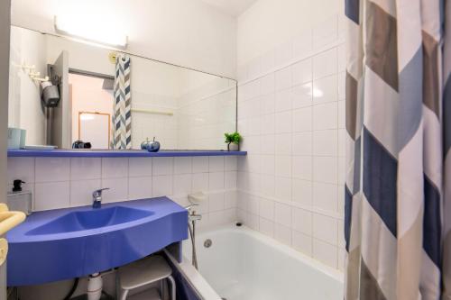 La salle de bains est pourvue d'un lavabo bleu et d'une baignoire. dans l'établissement Résidence le Village de Cap Esterel - maeva Home - Appartement vue mer 2 pièces 4 personnes - Confort MAE-9963, à Saint-Raphaël