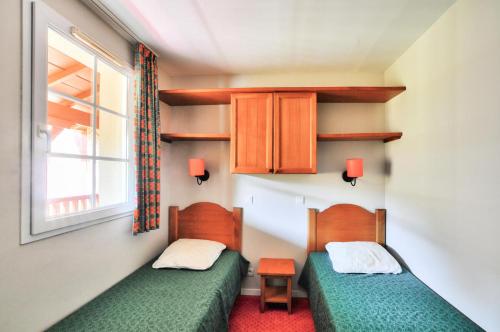 deux lits dans une petite pièce avec une fenêtre dans l'établissement La résidence du Lac - maeva Home - Appartement 2 pièces 4 personnes - Sélection MAE-5243, à Monflanquin