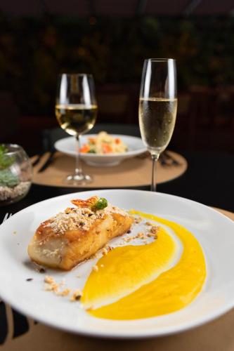 a plate with a piece of food and two glasses of wine at Duke Beach Hotel Maresias in Maresias