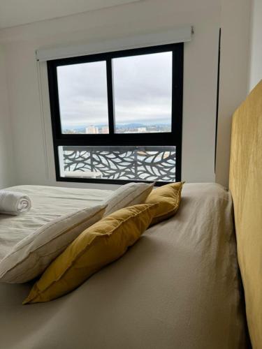 a bed with a pillow in front of a window at Departamento Confort AVI in Salta