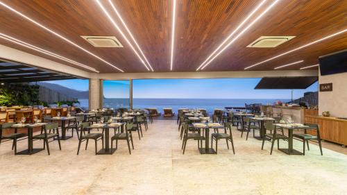 a restaurant with tables and chairs and a view of the ocean at Duke Beach Hotel Maresias in Maresias
