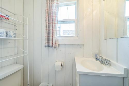 a white bathroom with a sink and a window at Cozy & Easy - Steps to the Sand in Oscoda