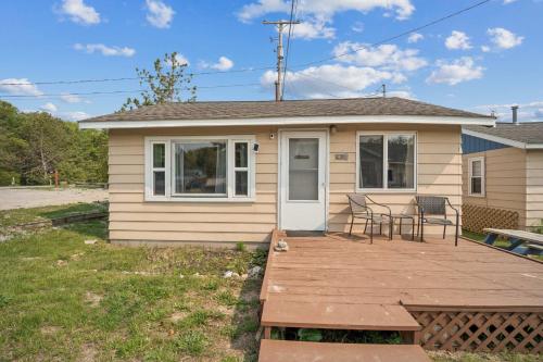 a small house with a deck with chairs and a table at Cozy & Easy - Steps to the Sand in Oscoda