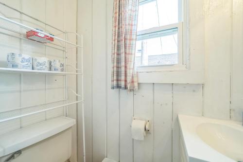 a white bathroom with a sink and a window at Cozy & Easy - Steps to the Sand in Oscoda