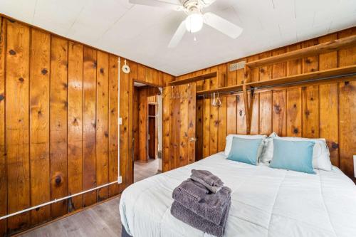 a bedroom with a bed with wooden walls and a ceiling at Cozy & Easy - Steps to the Sand in Oscoda