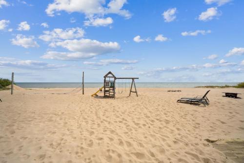 a playground on a sandy beach with the ocean at Cozy & Easy - Steps to the Sand in Oscoda