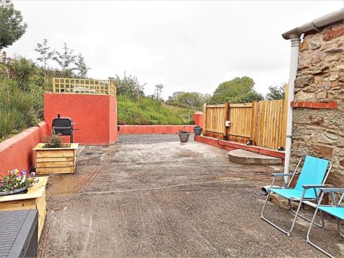 a patio with two chairs and a grill at 2 bed property in Brynteg West Wales 81353 in Llanwenog