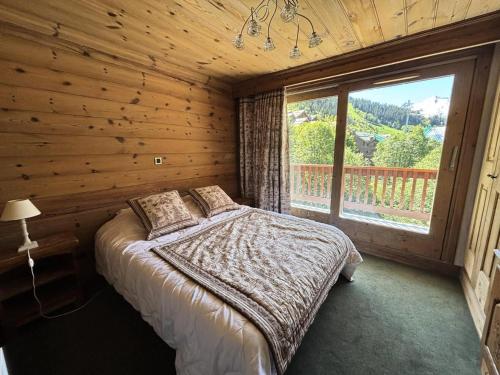 une chambre avec un lit et une grande fenêtre dans l'établissement Résidence Les Brimbelles - Appartement 3 pièces pour 6 personnes situé dans le centre de Méribel proche des commerces et des pistes de ski MAE-2041, à Les Allues