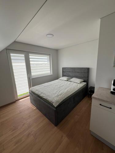 a bedroom with a bed and two windows at Svečių namai PAS MEŠKĄ in Karklė