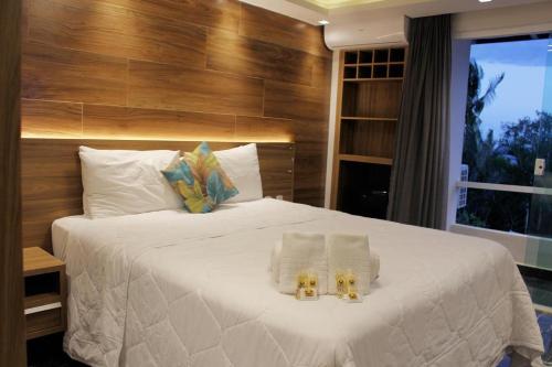 a bedroom with a large white bed with two towels at Hotel Pousada Casacolina in Búzios