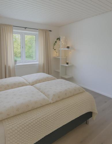 a white bedroom with a large bed and a window at Guldmark in Lemvig