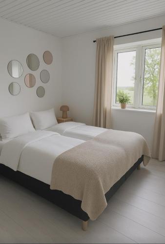 a white bedroom with a large bed and a window at Guldmark in Lemvig