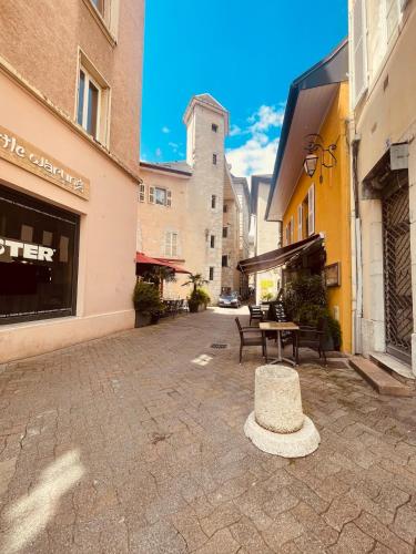 une cour avec une table, des chaises et des bâtiments dans l'établissement La Cachette du Prince Parking included, à Chambéry