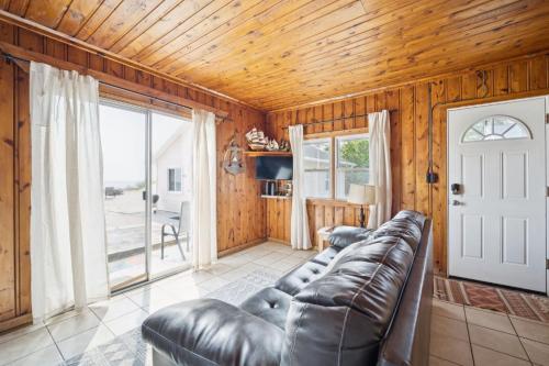 a living room with a leather couch and wooden walls at Light-Filled Near the Shore in Oscoda