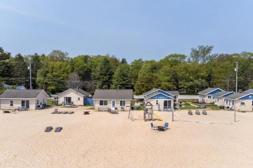 a sandy beach with chairs and houses on it at Lake Views with Big Windows & Bath in Oscoda