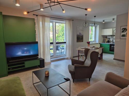 a living room with a couch and a tv and a table at Apartament z widokiem na Dom Oficera in Borne Sulinowo
