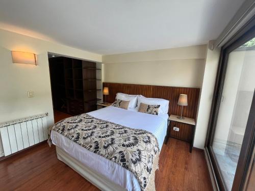 a bedroom with a large bed and a window at Abedul Apartamentos in San Martín de los Andes