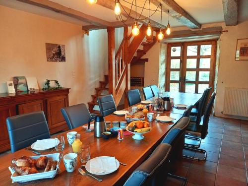 een grote houten tafel met stoelen en een lange tafel met eten erop bij Au pays de Jacquou : Chambre d’hôtes et table d’hôtes in Fossemagne