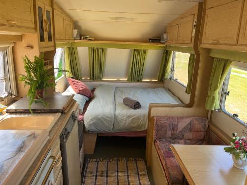 a small room with a bed in the back of a caravan at Vintage Nest by the Sea in Saraiķi